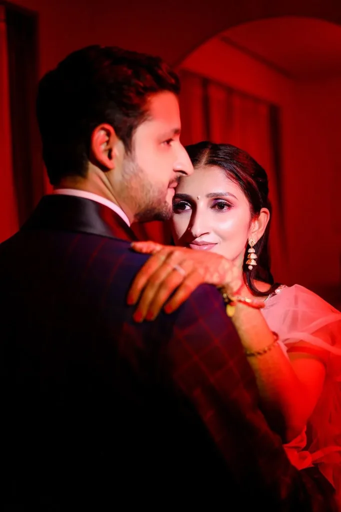 Groom and bride close together in warm red light, an intimate wedding portrait