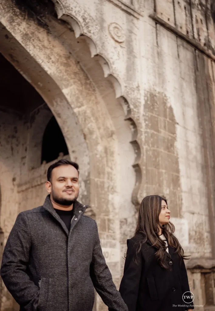 Couple standing before carved stone arches of an old monument during their pre-wedding shoot