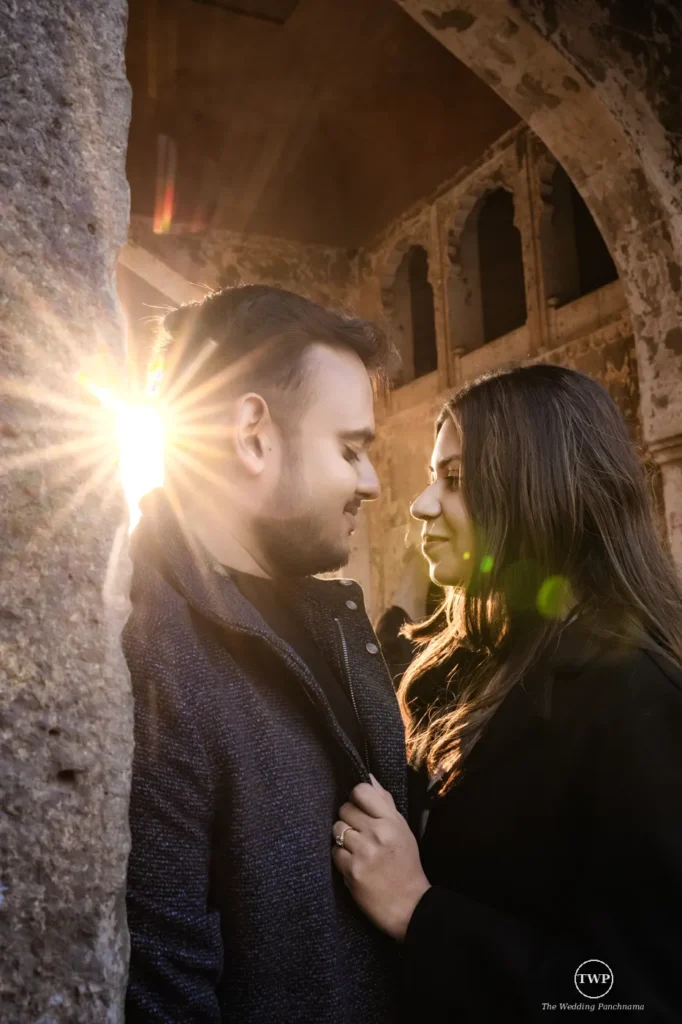 Couple framed by a heritage stone archway with evening sun flare during a pre-wedding shoot near Mandu