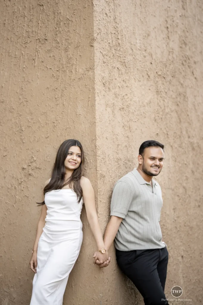 Couple holding hands against a clean textured wall during a minimalist pre-wedding shoot in Indore