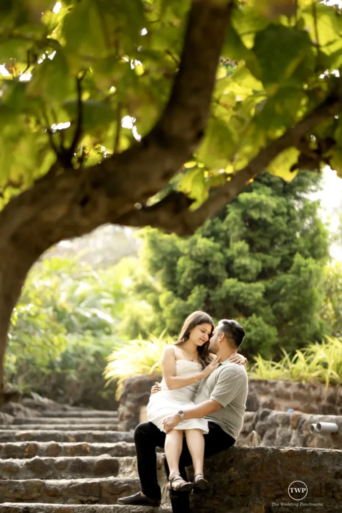 Couple sitting together on stone steps under a tree in a garden near Indore