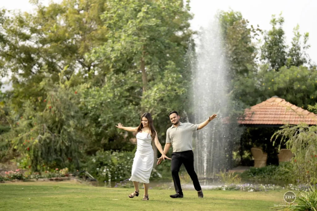 Joyful couple dancing on a lawn by a fountain during a couple shoot near Indore