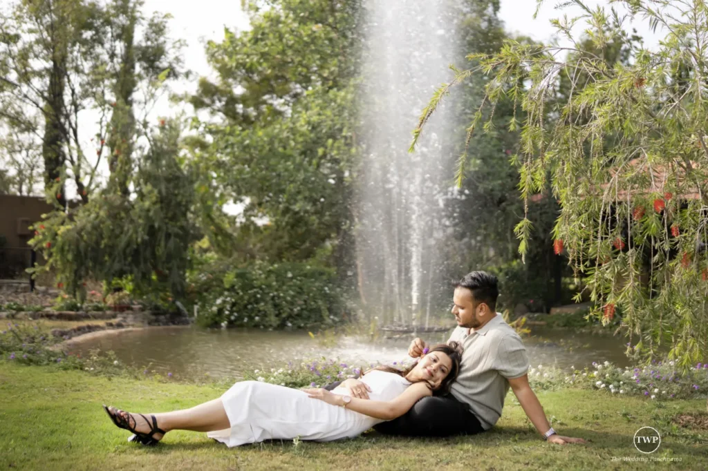 Couple relaxing on the grass by a fountain during a couple shoot near Indore