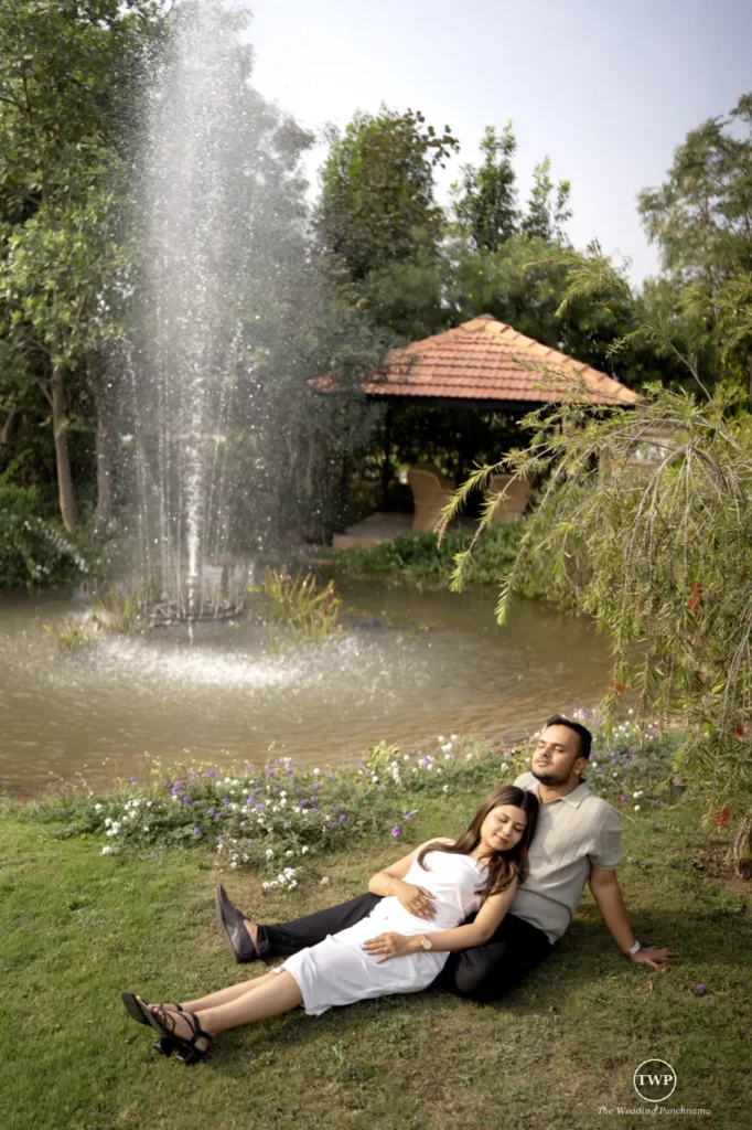 Couple relaxing on the grass by a fountain during a save the date photoshoot near Indore
