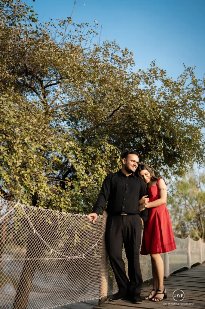 Couple standing on a wooden bridge among trees during an anniversary photoshoot near Indore