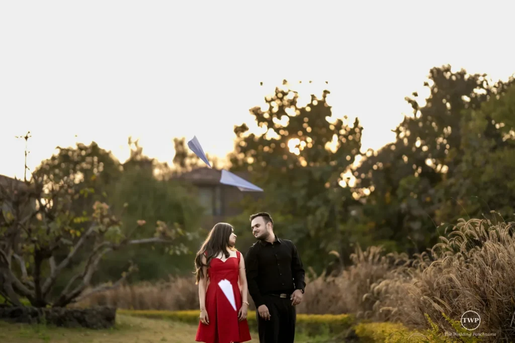 Couple laughing together in a garden with paper planes during a couple shoot near Indore