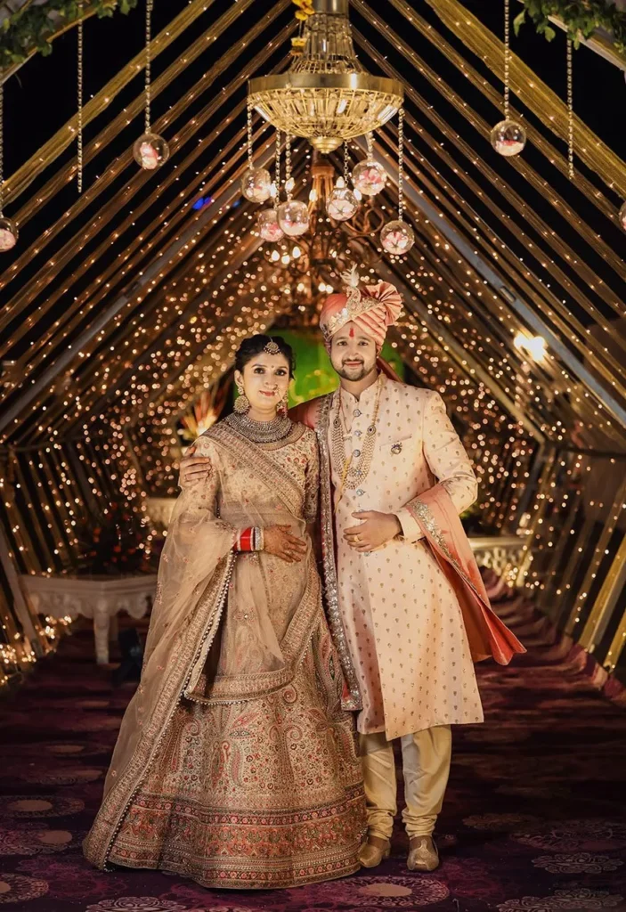 Couple in traditional outfits under fairy lights at a sangeet night wedding in Indore by The Wedding Panchnama